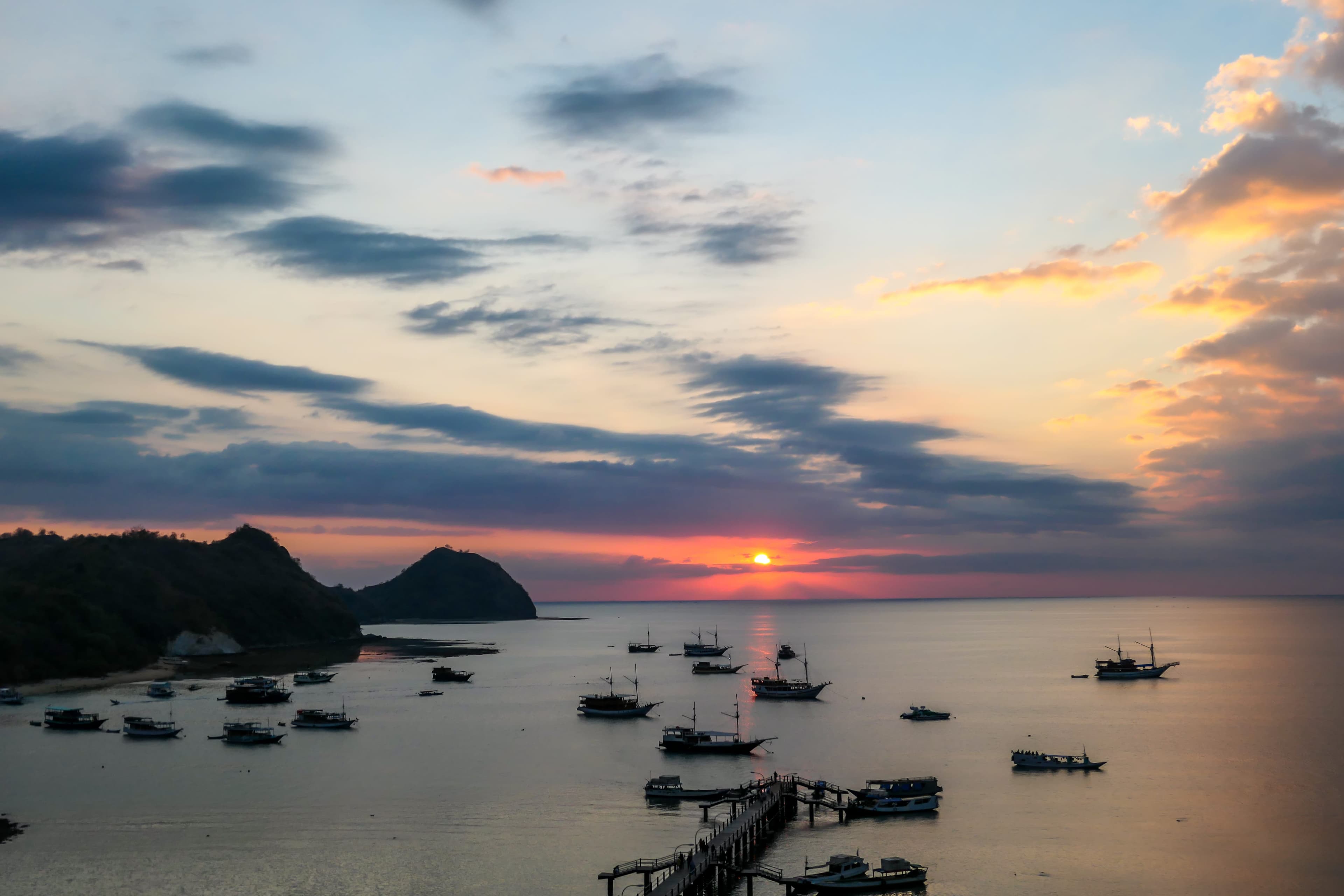 Traditional phinisi vessels moored in Labuan Bajo harbour at golden hour, Komodo National Park